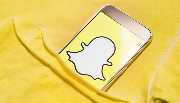 Dieses Foto zeigt ein Smartphone, auf dessen Screen großformatig der Snapchat-Geist auf gelbem Untergrund zu sehen ist.